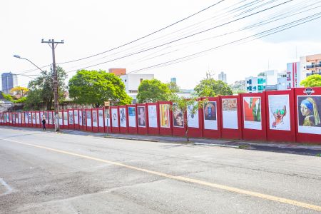 Foto de um muro vermelho com várias obras de arte colado no muro